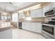 Well-lit kitchen with stainless appliances, white cabinets, and view into breakfast nook at 456 Pinewood Lake Dr, Venice, FL 34285