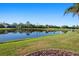 Scenic pond view with lush greenery and reflections under a clear blue sky at 456 Pinewood Lake Dr, Venice, FL 34285