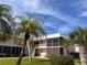 Condo exterior featuring a screened porch, stairs, and palm trees under a blue sky at 460 Base E Ave # 129, Venice, FL 34285