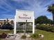 The Sentinel community sign surrounded by lush greenery and parking area at 460 Base E Ave # 129, Venice, FL 34285
