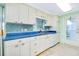 Well-lit kitchen boasts white cabinets, blue countertops, mosaic backsplash, and stainless steel appliances at 483 Circlewood Dr # O14, Venice, FL 34293