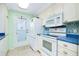 Bright kitchen features white appliances, white cabinetry, blue countertops, and access to outside at 483 Circlewood Dr # O14, Venice, FL 34293