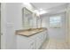 Bathroom featuring a double vanity with granite countertops, white cabinets, and modern fixtures at 49 Sandstone Cir, Venice, FL 34293