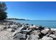 Scenic view of a serene beach with large rocks, calm turquoise water, and a distant cityscape on the horizon at 49 Sandstone Cir, Venice, FL 34293