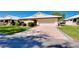 Charming home featuring a patterned brick driveway leading to an attached garage and landscaped front yard at 49 Sandstone Cir, Venice, FL 34293