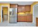 Open kitchen with stainless steel refrigerator, granite countertops, and tile flooring at 49 Sandstone Cir, Venice, FL 34293