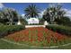 Beautiful community sign with bright red flowers and palm trees at The Plantation Golf & Country Club at 503 Clubside Cir # 47, Venice, FL 34293