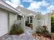 Charming front entrance surrounded by white trellis features stone pavers and lush landscaping at 503 Clubside Cir # 47, Venice, FL 34293