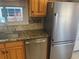 Close up of the kitchen sink and dishwasher with stainless steel refrigerator and wooden cabinets at 508 Vasto Dr, Venice, FL 34285