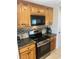 Kitchen featuring stainless steel oven with wooden cabinetry and dark granite countertops at 508 Vasto Dr, Venice, FL 34285