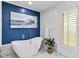 Bright bathroom featuring a modern soaking tub, blue accent wall, and stylish marble flooring at 524 Lyons Bay Rd, Nokomis, FL 34275