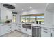 Modern white kitchen with stainless steel appliances, quartz countertops, and a large window overlooking the water at 524 Lyons Bay Rd, Nokomis, FL 34275
