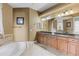 Bright bathroom featuring a soaking tub, granite countertops, and wooden cabinetry at 5550 Rock Dove Dr, Sarasota, FL 34241