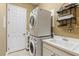 Bright laundry room with stacked washer and dryer and built in shelving with a white utility sink at 5550 Rock Dove Dr, Sarasota, FL 34241