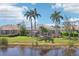 Water view of the rear of this home featuring a screened-in patio and palm trees at 614 Pond Willow Ln, Venice, FL 34292