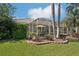 View of the screened-in patio of this home complete with tropical landscaping and brickwork at 614 Pond Willow Ln, Venice, FL 34292