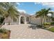 Charming single-story home featuring tropical landscaping, a paver driveway, and a two-car garage at 614 Pond Willow Ln, Venice, FL 34292