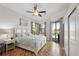 Cozy main bedroom with wood floors, ceiling fan, access to lanai, and a comfortable bed at 614 Pond Willow Ln, Venice, FL 34292