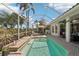 Inviting screened-in pool area with brick-paved patio, surrounded by lush tropical landscaping at 614 Pond Willow Ln, Venice, FL 34292