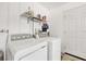 Functional laundry area featuring a washer, dryer, storage shelves, and white door at 6392 Coliseum Blvd, Port Charlotte, FL 33981