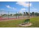 Community tennis court surrounded with a fence and a bench for rest at 6392 Coliseum Blvd, Port Charlotte, FL 33981