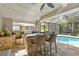 Elegant outdoor kitchen features a built-in grill, bar seating, stone accents, and views of the screened pool area at 7324 Links Ct, Sarasota, FL 34243