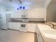 Bright kitchen with white cabinets and appliances plus tiled floors offers an efficient workspace at 915 Tartan Dr # 29, Venice, FL 34293