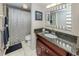 Cozy bathroom featuring a granite countertop, decorative art, and a shower with modern shower curtain at 950 Tarpon Center Dr # 506, Venice, FL 34285