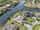 Waterfront home featuring a screened-in pool, boat dock, and lush landscaping on a sunny day at 9542 Spring Cir, Port Charlotte, FL 33981