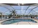 Screened-in pool with waterfront views features a patio area with lounge chairs and a blue umbrella at 9542 Spring Cir, Port Charlotte, FL 33981