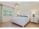 Bright bedroom features a king bed, wood floors, white trim, and a stylish light fixture at 9800 Bright Water Dr, Englewood, FL 34223