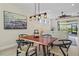 Dining room features a modern table with industrial light fixture, art, and view of screened lanai and backyard at 9800 Bright Water Dr, Englewood, FL 34223