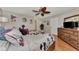 This bedroom boasts wood floors, neutral walls, a dresser with TV, and ceiling fan at 1048 Ulrey Ln, Englewood, FL 34223