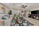 Bright living room featuring ceiling fan, tiled floor, shuttered windows, and access to other living spaces at 1048 Ulrey Ln, Englewood, FL 34223