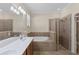 Bright bathroom featuring double vanity, soaking tub, and glass-enclosed shower at 12565 Canavese Ln, Venice, FL 34293