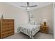 Well-lit bedroom features a ceiling fan, palm-themed decor, dresser and nightstand at 12565 Canavese Ln, Venice, FL 34293