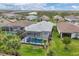 Aerial view of a house with a screened-in pool and spa, surrounded by lush landscaping and other well-maintained homes at 13165 Rinella St, Venice, FL 34293