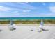 Ocean view from a deck with patio seating and blue umbrellas overlooking the beach at 1555 Tarpon Center Dr # 255, Venice, FL 34285