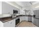 Well-lit kitchen features white cabinets, stainless steel appliances, and a granite countertop at 1572 Monarch Dr, Venice, FL 34293