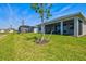 Spacious backyard featuring a grassy lawn, mature trees, and a covered patio area at 1606 Cedar Valley Dr, Port Charlotte, FL 33953
