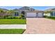 Beautiful single-Gathering home featuring a three-car garage, lush landscaping, and a brick driveway at 1606 Cedar Valley Dr, Port Charlotte, FL 33953