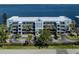 Waterfront condominium building featuring a coastal blue facade, lush landscaping, and balconies with stunning water views at 1750 Jamaica Way # 322, Punta Gorda, FL 33950