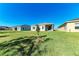 An image of a green backyard with a clear blue sky, with neighboring homes on either side at 1766 Sunset Preserve Way, Port Charlotte, FL 33953