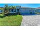 Charming single-story home with well-manicured lawn, lush landscaping, and a gray brick driveway at 1766 Sunset Preserve Way, Port Charlotte, FL 33953