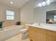 Bright bathroom with a bathtub, vanity, and neutral tile, creating a clean and inviting space at 1769 Manasota Beach Rd, Englewood, FL 34223