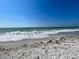 Scenic beach view featuring white sand and gentle waves under a clear blue sky at 1769 Manasota Beach Rd, Englewood, FL 34223