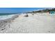Expansive beach view with sunbathers and blue umbrellas along the shore at 1769 Manasota Beach Rd, Englewood, FL 34223