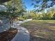 Paver walkway leading to a well-manicured lawn and mature trees at 1769 Manasota Beach Rd, Englewood, FL 34223