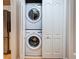 Laundry closet with stacked washer and dryer and white bi-fold doors at 1769 Manasota Beach Rd, Englewood, FL 34223