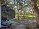 View of wooded yard from the screened-in porch with lush green grass and mature trees at 1769 Manasota Beach Rd, Englewood, FL 34223